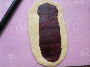 把豆沙也擀成椭圆形，比面团的形状略小一圈，然后把豆沙铺在面团上