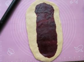 把豆沙也擀成椭圆形，比面团的形状略小一圈，然后把豆沙铺在面团上