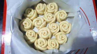 8寸戚风模具中垫上油纸（或者刷一层黄油），放进切好的玫瑰花，先放外层，在放中间。盖保鲜膜二次发酵，我还是放暖气上的，如果放烤箱发酵，下面要放一杯水增加湿度。