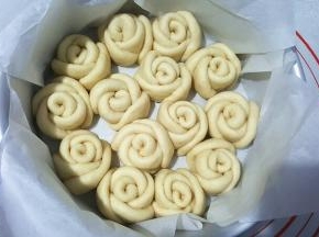 8寸戚风模具中垫上油纸（或者刷一层黄油），放进切好的玫瑰花，先放外层，在放中间。盖保鲜膜二次发酵，我还是放暖气上的，如果放烤箱发酵，下面要放一杯水增加湿度。