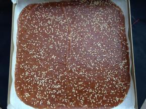 擀均匀后，揭开保鲜膜，在上面撒上白芝麻，然后盖上保鲜膜轻轻的再擀一遍使芝麻粘进肉馅里，最后揭去保鲜膜移入烤盘内