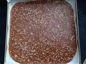 擀均匀后，揭开保鲜膜，在上面撒上白芝麻，然后盖上保鲜膜轻轻的再擀一遍使芝麻粘进肉馅里，最后揭去保鲜膜移入烤盘内