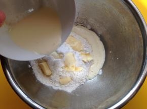 将低粉和糖粉、盐、小苏打混合拌匀，加入黄油，然后将酵母牛奶混合液倒入