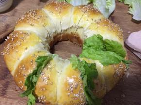 用面包刀将中间切开，不要切断，抹上沙拉酱，夹上生菜叶