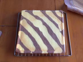 拿出一张新油纸放在蛋糕上面，翻面趁温热卷起