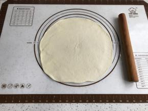 取出面团，擀成比披萨盘大一圈的面皮。