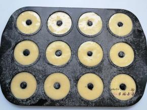 甜甜圈模具提前刷一层黄油，并筛一层低筋面粉防粘，然后依次挤入面糊，挤一半的时候撒上一些蔓越莓干，然后再继续挤满