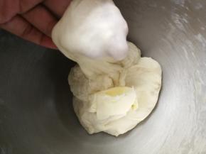 约8分钟后，面团能拉出粗膜，加入盐和软化的黄油，继续和面