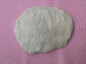 面团移至揉面垫上，按扁排气