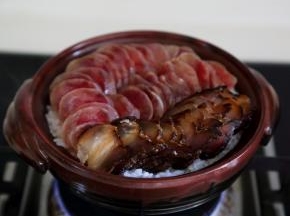 煮开后，当饭开始收水，可以看到饭表面有一个个的洞，就将切好的肉片码入。
