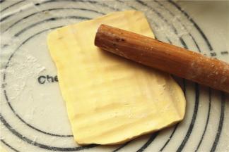 来处理黄油。很多人觉得没有片状黄油就没法开酥，完全不是这么回事啊，普通黄油一样做出漂亮的可颂呢。先把黄油切成厚片，冷藏的黄油（切记是冷藏不是冷冻），刚拿出来会比较硬，但没关系，案板上撒粉，黄油块上也撒粉，用擀面杖敲击黄油，几分钟后，黄油就会变得很听话，也很柔软，同时在敲击下变大变薄。敲击的时候要用力要均匀。