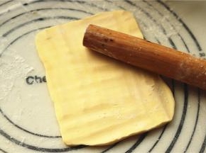 来处理黄油。很多人觉得没有片状黄油就没法开酥，完全不是这么回事啊，普通黄油一样做出漂亮的可颂呢。先把黄油切成厚片，冷藏的黄油（切记是冷藏不是冷冻），刚拿出来会比较硬，但没关系，案板上撒粉，黄油块上也撒粉，用擀面杖敲击黄油，几分钟后，黄油就会变得很听话，也很柔软，同时在敲击下变大变薄。敲击的时候要用力要均匀。