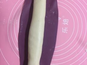 将紫薯面团擀成长方形薄片，将白面团搓成等长的面条放在紫薯面片上；