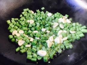 四季豆煸炒到5成熟时放入蒜片一起煸炒。