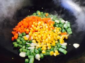 当四季豆煸炒至9成熟放入胡萝卜粒和玉米粒，翻炒均匀。