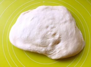 将发酵好的面团放在揉面垫上按压排出大气孔