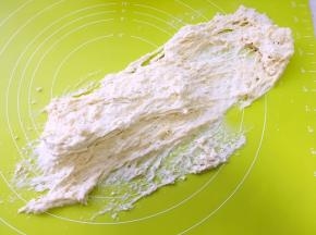 刚开始面团水份比例大，会有一些粘手，借用刮板将面团收成团，之后再用手掌像前推揉，反复推揉15分钟左右，面团筋度变大，再配合抓起面团摔打几下