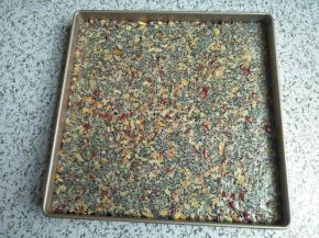 戴上胶手套稍微整平牛轧糖，让其平铺在方盘中，再用硅胶擀面杖滚压，让表面更光滑平整