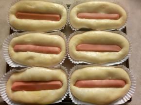 把香肠放在面包中间，用手指按到底。挤上番茄酱和沙拉酱。