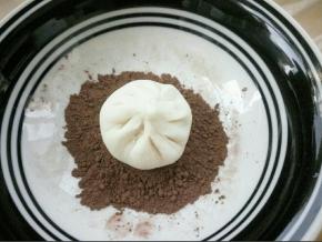 放在可可粉上，晃动盘子也好，转动包子也行，使包子的背面均匀沾上可可粉，边缘也要沾到，多余的粉抖下去