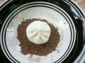 放在可可粉上，晃动盘子也好，转动包子也行，使包子的背面均匀沾上可可粉，边缘也要沾到，多余的粉抖下去