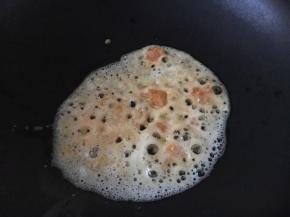 热锅凉油，放入鸭蛋黄，用铲子把蛋黄碾碎。