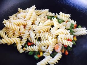 把煮好的意面放入炒好的四季豆虾仁中。