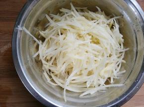 将土豆用擦丝器擦成丝状