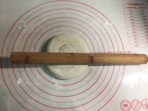 把面卷用手轻轻按扁，再用擀面杖擀圆。电饼铛可以开始预热。