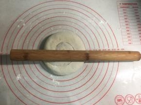 把面卷用手轻轻按扁，再用擀面杖擀圆。电饼铛可以开始预热。