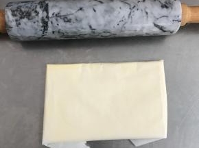 将黄油取出，切成小块状，用油纸包好，擀成长方形的薄片，大概7mm厚。