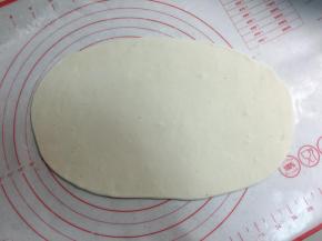 把一份面团用手揉圆按扁，擀成椭圆形的薄厚均匀的薄片。