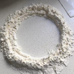 面粉放至桌面，中间划圈留出一个小圆