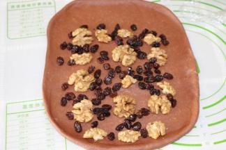 取一块擀成3mm后的长方形，铺上核桃仁和葡萄干，上端留出3cm空位