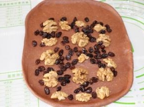 取一块擀成3mm后的长方形，铺上核桃仁和葡萄干，上端留出3cm空位