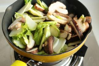 加入儿菜和香菇，继续翻炒至变软。