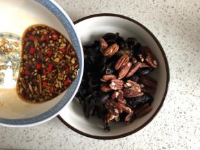 把碧根果倒入木耳内，然后浇上酸辣汁