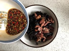把碧根果倒入木耳内，然后浇上酸辣汁