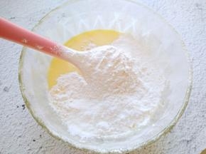 将蛋黄加入到酸奶中拌匀，再筛入低筋面粉和玉米淀粉。