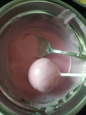 把棒棒糖蛋糕放到融化的巧克力里滚一圈，这样整个棒棒糖蛋糕就都会粘上巧克力了！
提起棒棒糖蛋糕静置一会等巧克力凝固就可以了