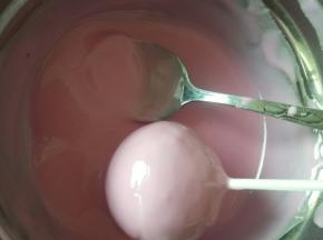 把棒棒糖蛋糕放到融化的巧克力里滚一圈，这样整个棒棒糖蛋糕就都会粘上巧克力了！
提起棒棒糖蛋糕静置一会等巧克力凝固就可以了