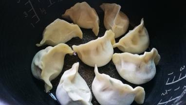 电饭煲内胆中刷油 饺子放好 按下煮饭键