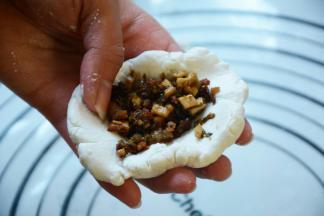 取一小部分揉圆压平包入适量的馅儿。