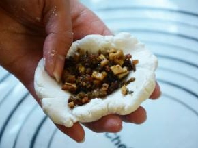 取一小部分揉圆压平包入适量的馅儿。