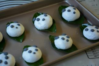 取一小部分黑糯米团分别捏出熊猫的五官粘贴在包好的叶儿粑相对的位置。