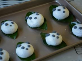 取一小部分黑糯米团分别捏出熊猫的五官粘贴在包好的叶儿粑相对的位置。