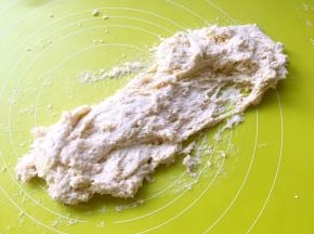 然后将面团倒在揉面垫上，用手掌一直向前推揉，就像洗衣服一样