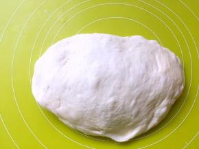 将面团取出，放在揉面垫上按压排出大气泡