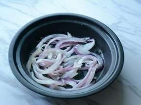 洋葱过滚水烫一下捞出放入盘中。