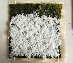 米饭用勺子背面按压铺平，上面留约3厘米左右不铺。